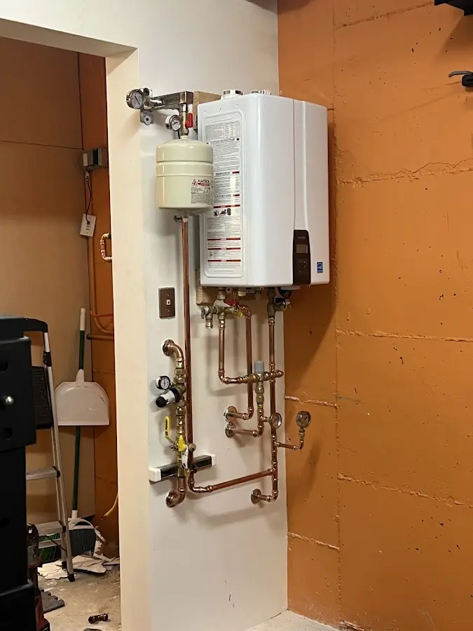 Plumbing technician inspecting water heater connections in Bay City